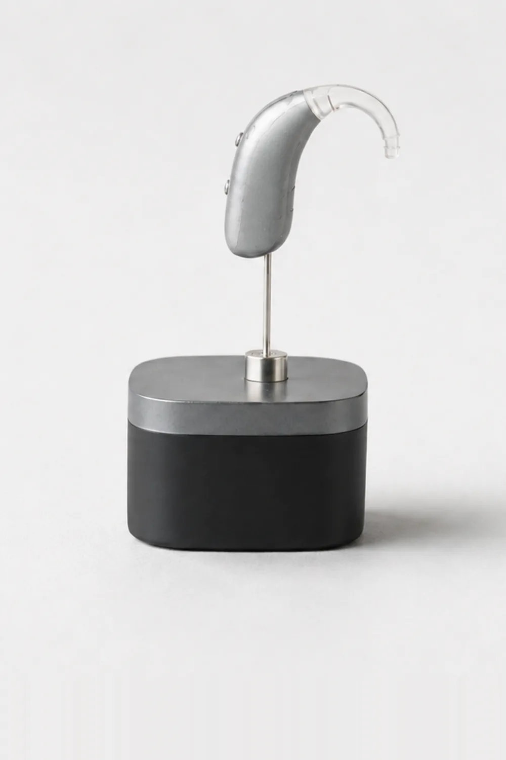 A hearing-aid lookalike on a machined steel and black presentation plinth.