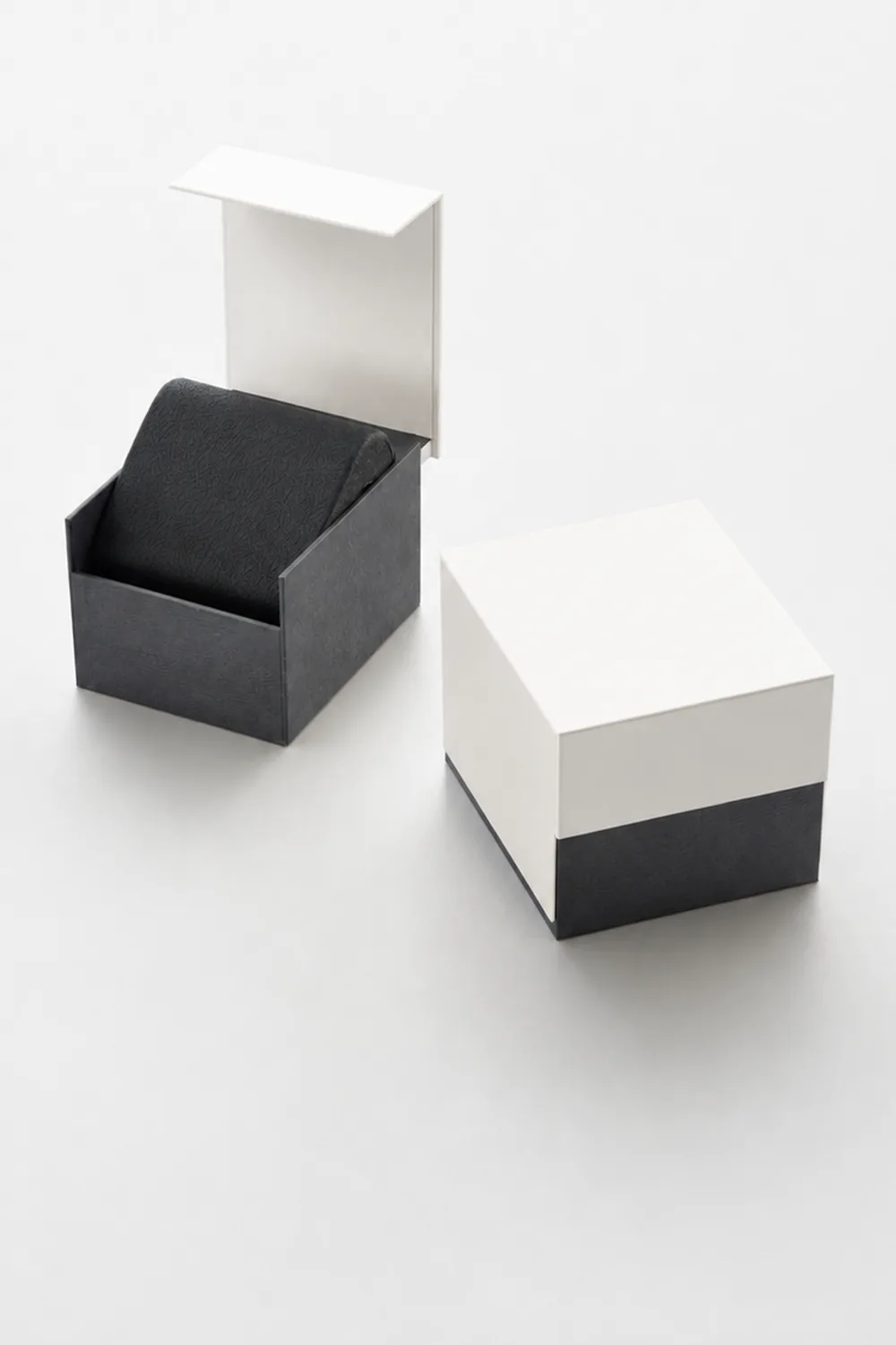 A two-part watch box in white and black, open beside its closed lid.